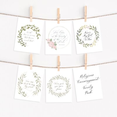 Religious encouragement note card pack staged hanging on twine with clothespins. Cards feature watercolor artwork and calligraphy messages