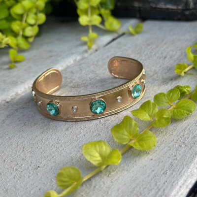 Gold cuff bracelet with green gemstones